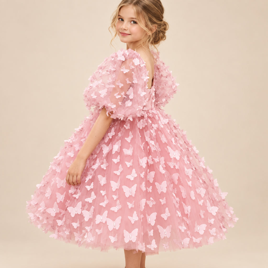 Pink dress with butterfly pattern worn by a child against a white background