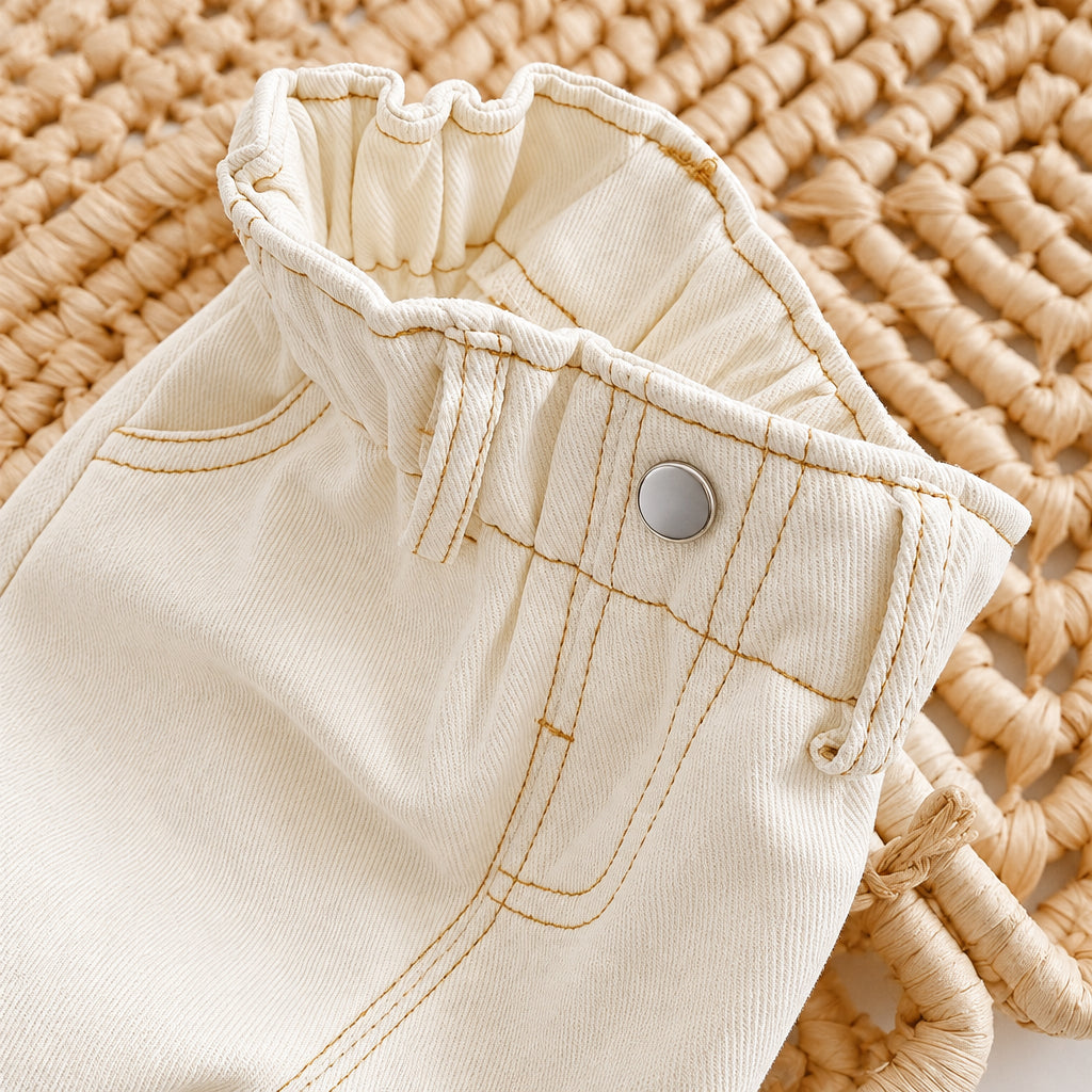 Close-up of beige denim shorts with a button on a textured beige background