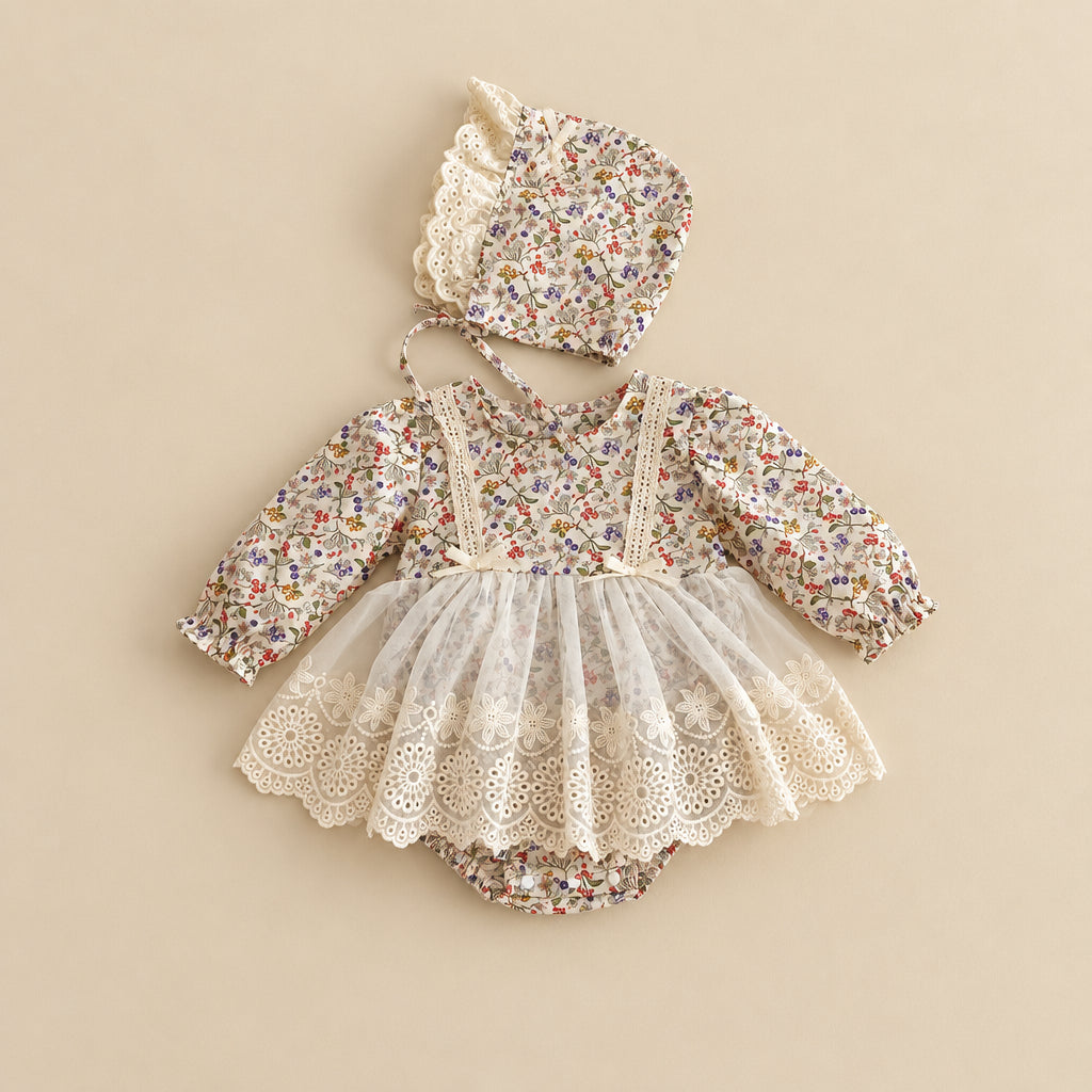 A baby girl's floral print romper and bonnet set, styled as a flat lay on a light beige background. The romper features a long-sleeve floral bodice with cream lace trim and a layered tulle tutu skirt.