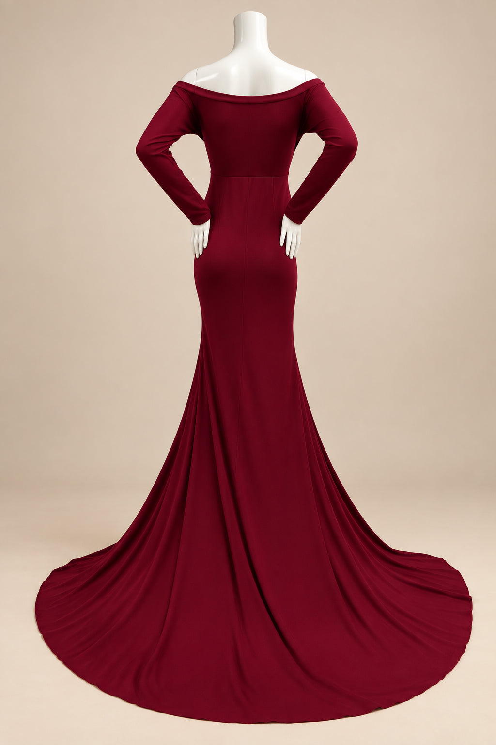 A long-sleeve off-the-shoulder mermaid gown in deep burgundy, displayed on a white mannequin with hands and a mannequin head. The dress features a fitted bodice and a flared skirt with a slight train, set against a white wall and a white shag rug.