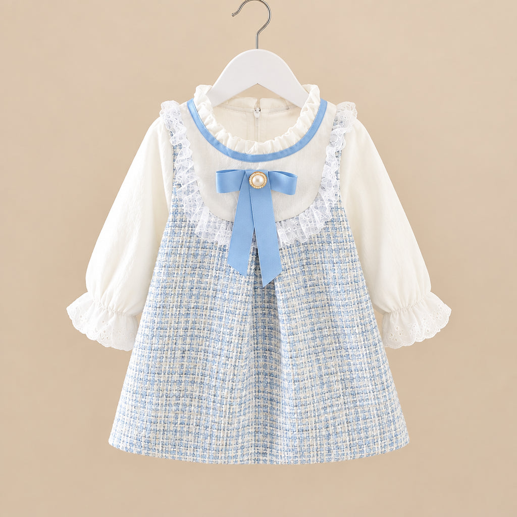 Children's dress with plaid skirt and white blouse on a hanger against a neutral background
