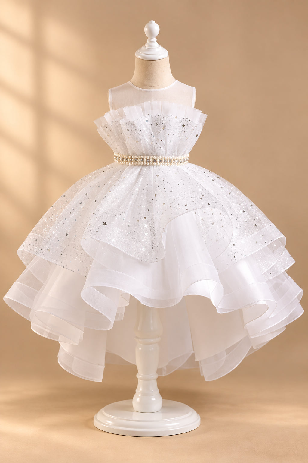 White children's dress with ruffled layers on a mannequin against a gray background