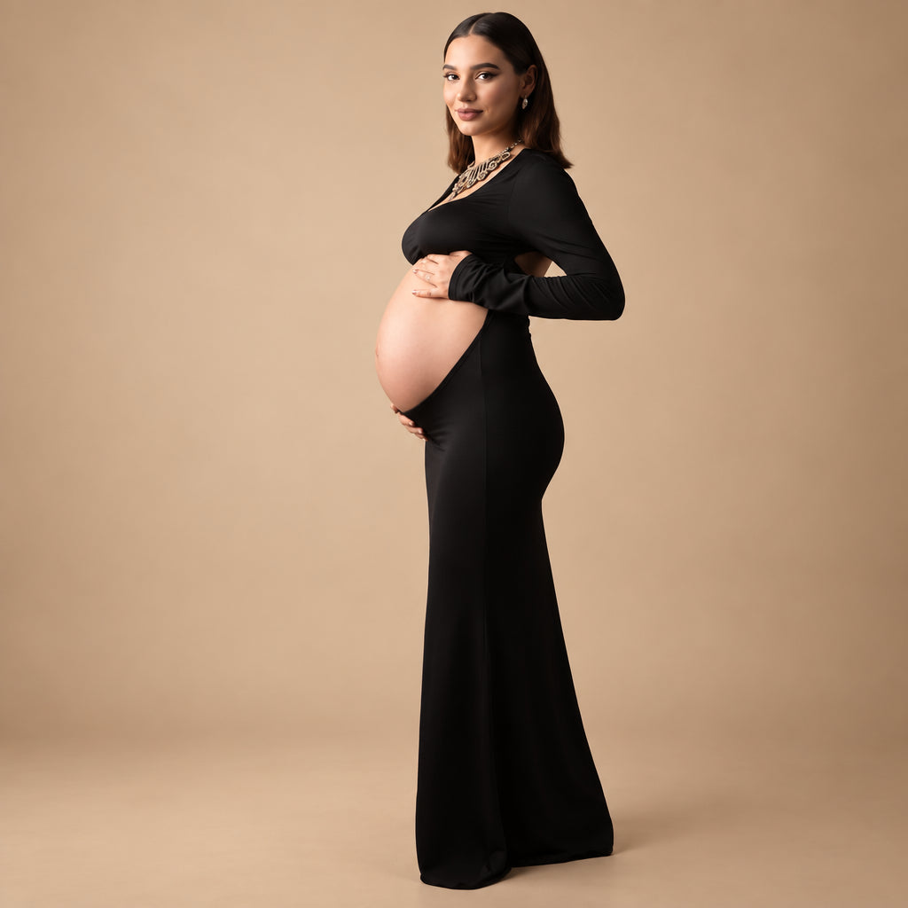 Pregnant woman in a black dress standing against a gray textured wall.