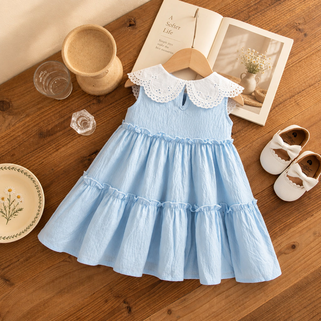 Light blue dress with white collar on a wooden surface with shoes and books.