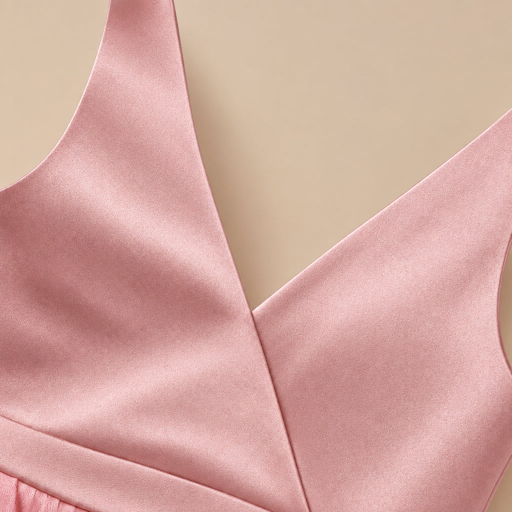 Close-up of a light pink wrap-style bra or bodysuit top showing the V-neckline and smooth satin-like fabric against a light gray background.