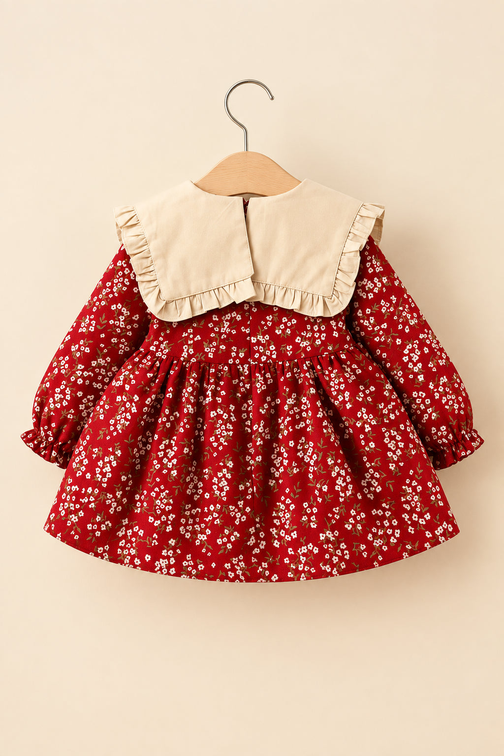 Red floral dress with beige collar on a hanger against a white background