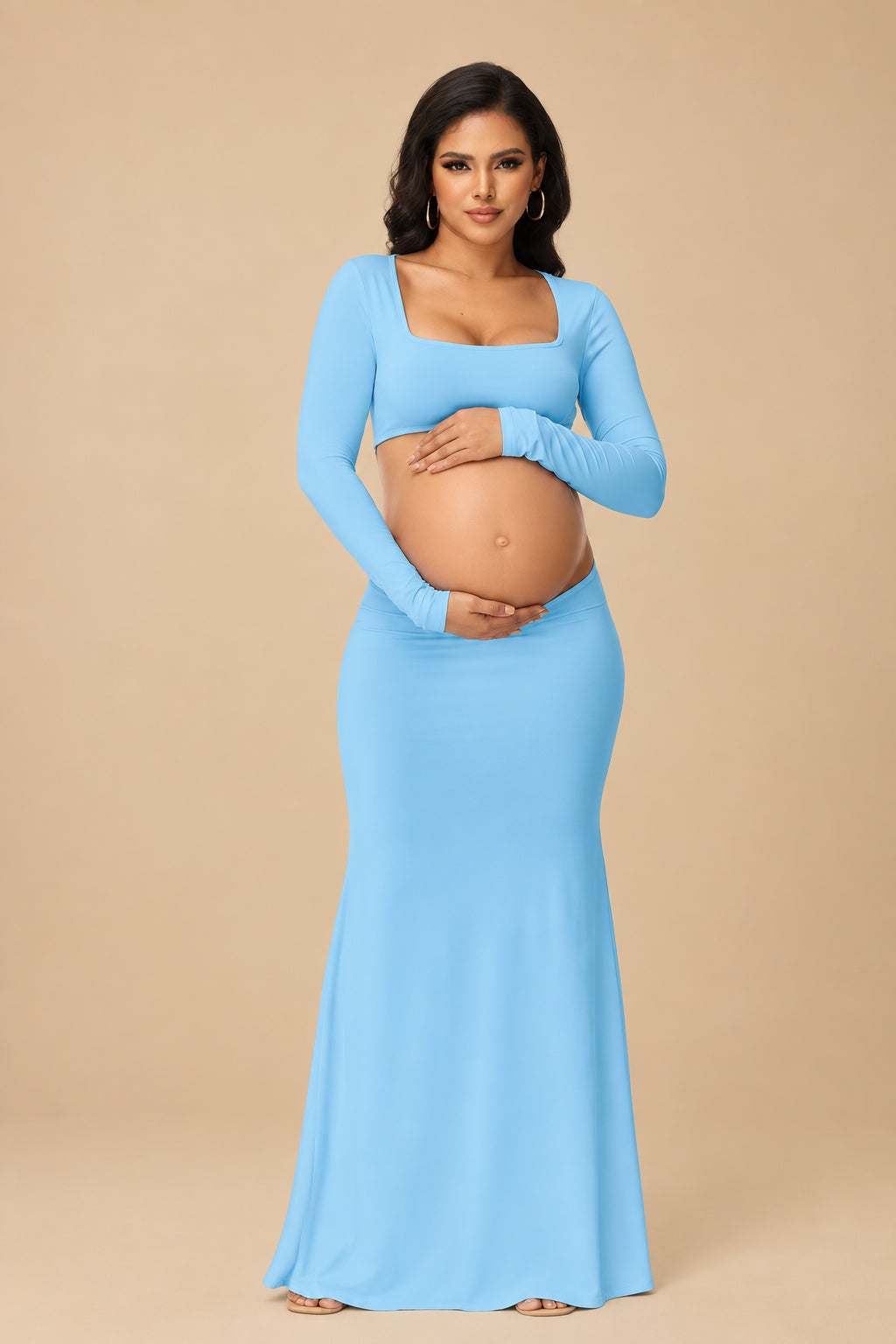 Pregnant woman wearing a light blue long-sleeve gown against a white curtain background